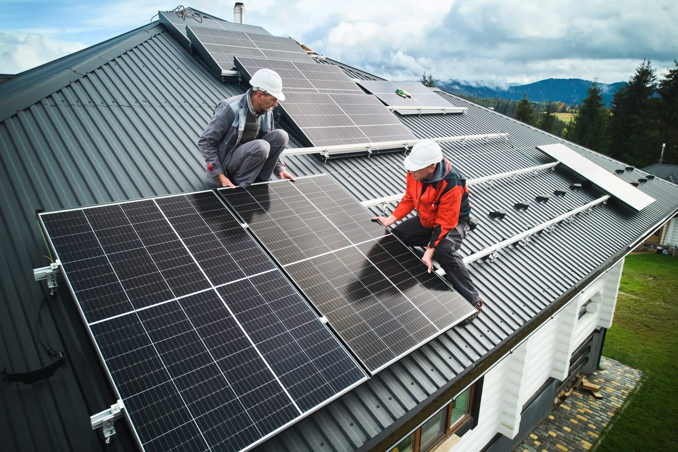 Men workers installing solar panels on roof of house.